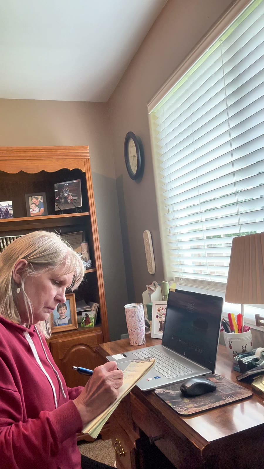 Carla at her home desk, writing notes on a legal pad next to her laptop